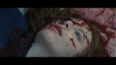 a woman with blood all over her face laying on a bed