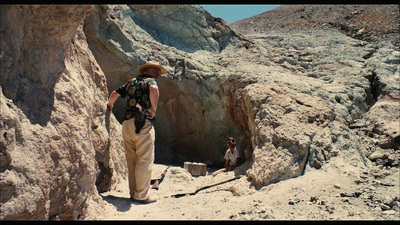 a man in a hat standing on a rocky cliff