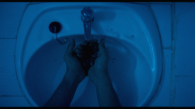 a person's hands holding a plunger in a blue lit bathroom