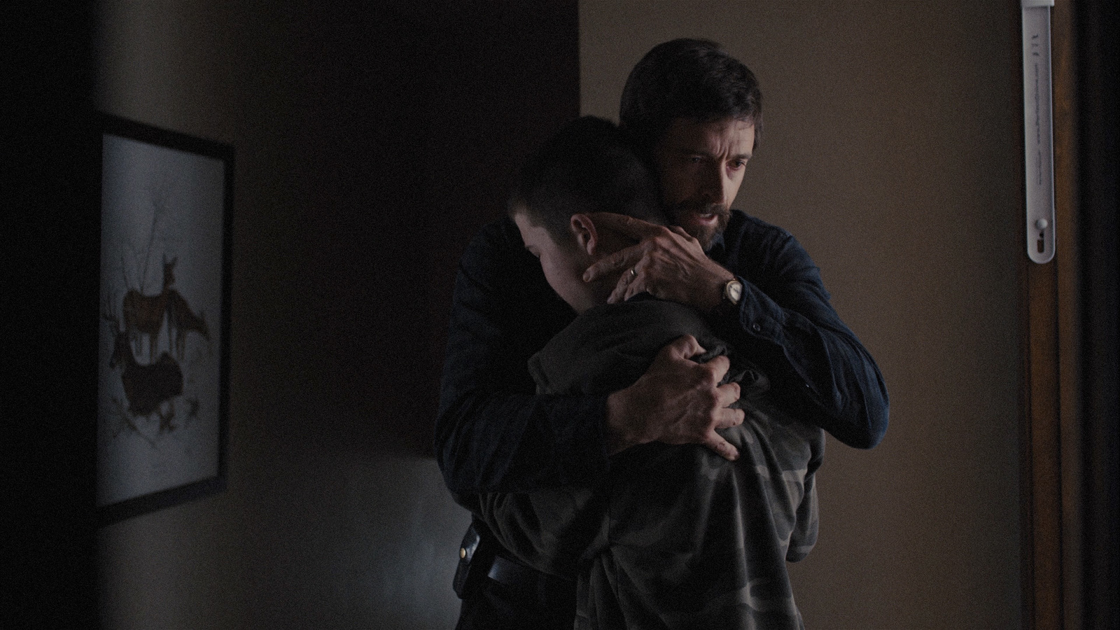 a man is hugging another man in a dark room