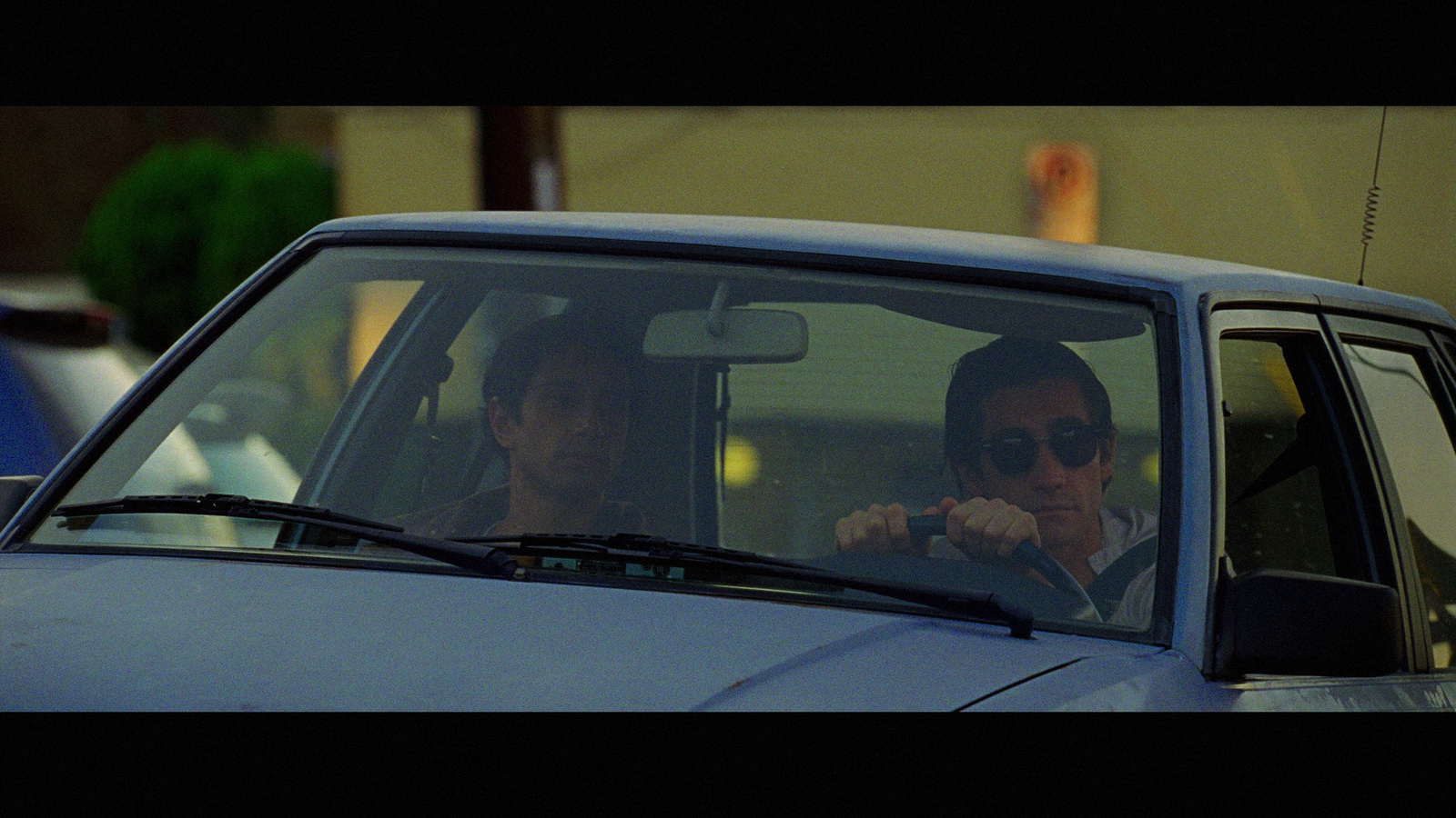 two men sitting in a car talking on the phone