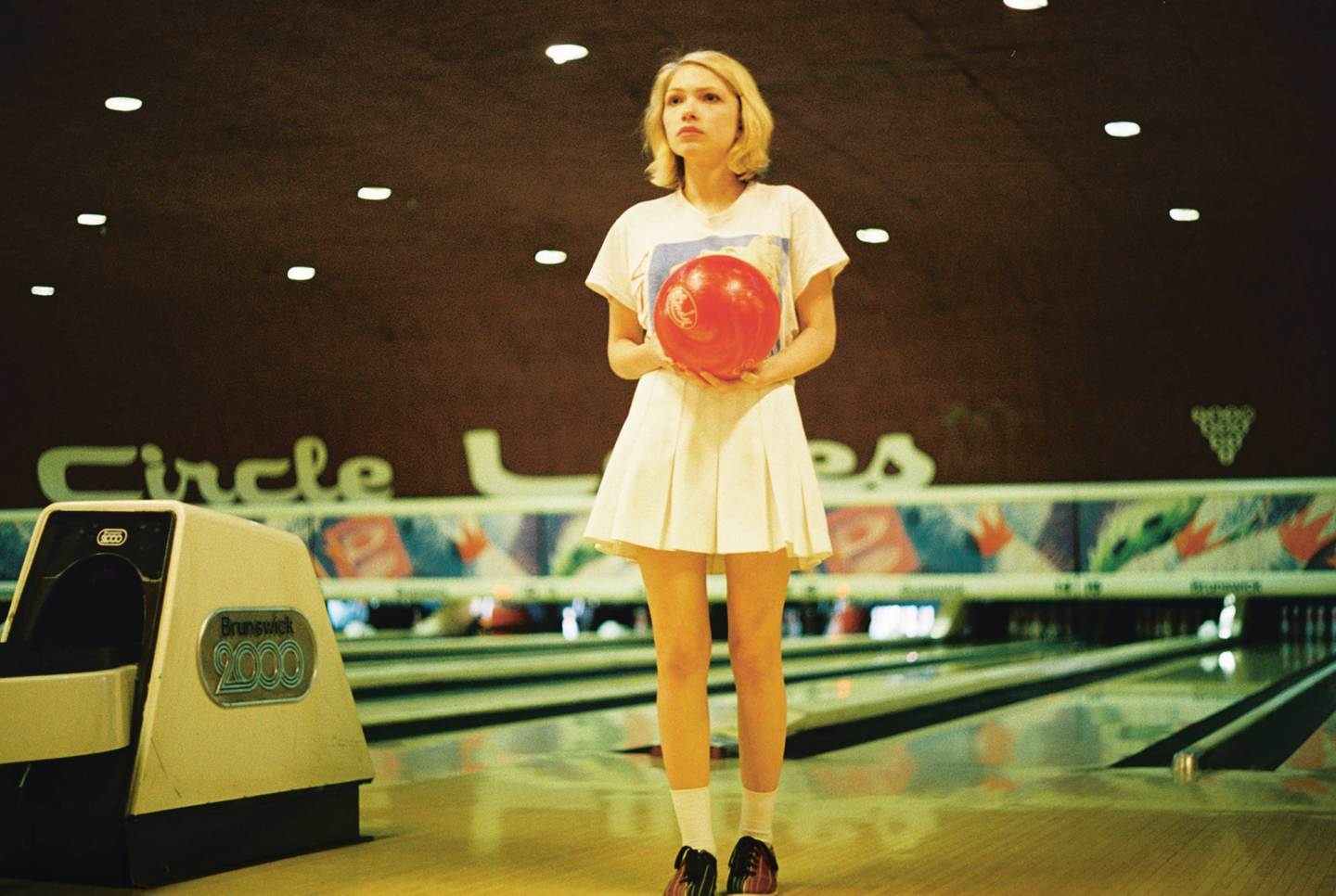 a woman holding a bowling ball in a bowling alley