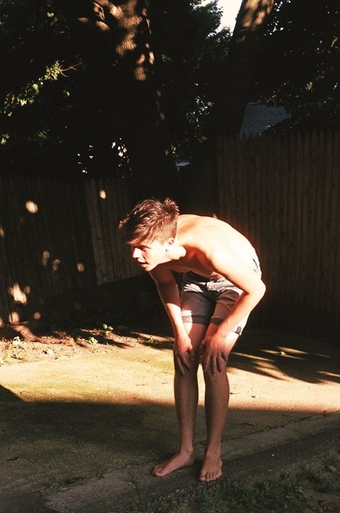 a man standing in a yard with his hands on his knees