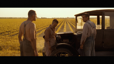 a group of men standing next to a truck in a field