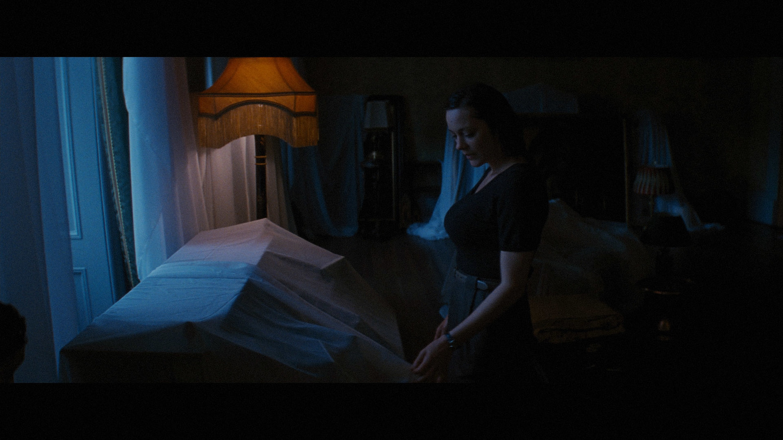 a woman standing next to a bed in a dark room