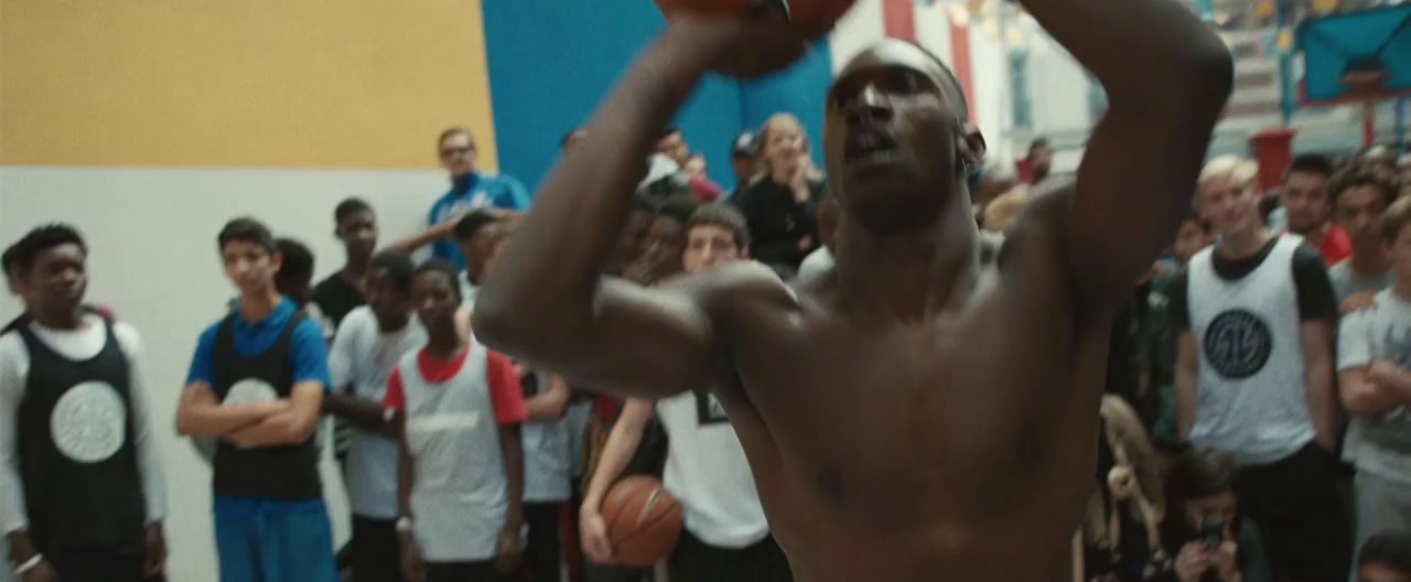 a shirtless man holding a basketball in front of a crowd