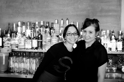 a couple of women standing next to each other in front of a bar