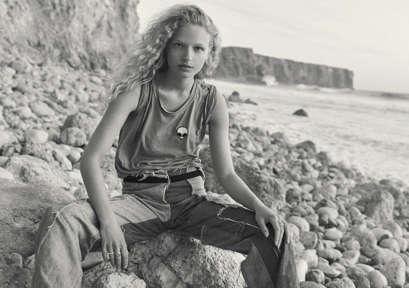 a woman sitting on a rock near the ocean