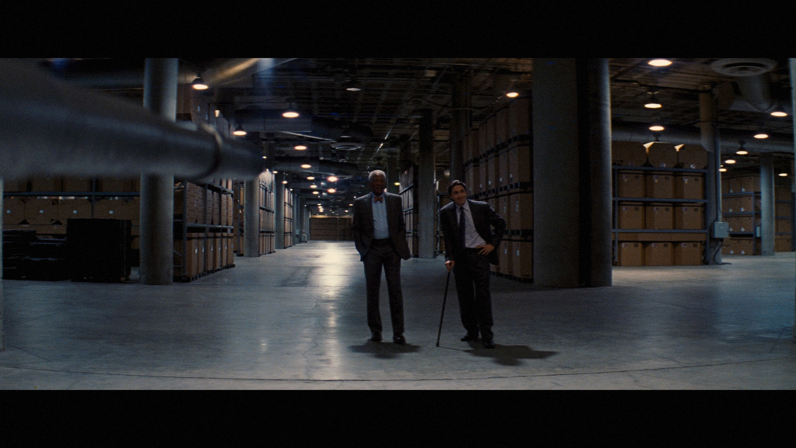 a couple of men standing next to each other in a warehouse