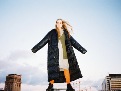 a woman in a black coat is standing on a skateboard