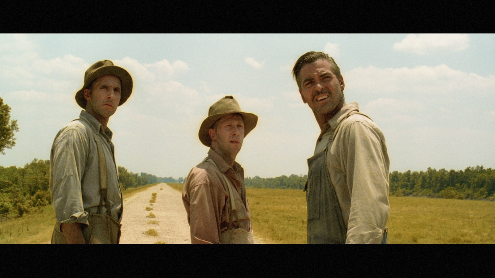 a group of men standing on top of a dirt road