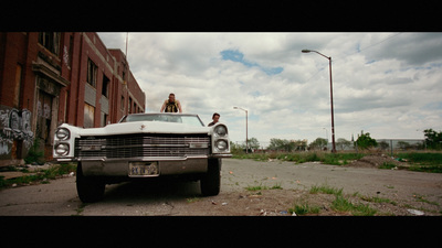 a man and a woman sitting on top of a car