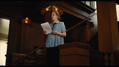 a woman standing at the top of a set of stairs holding a piece of paper