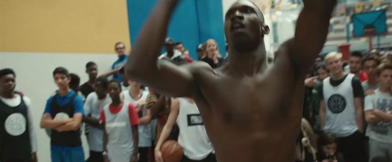 a shirtless man holding a basketball in front of a crowd