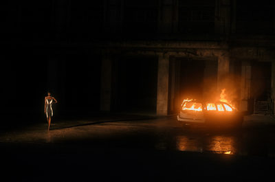 a woman standing next to a car on a dark street