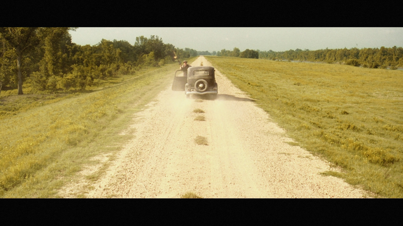 an old truck driving down a dirt road