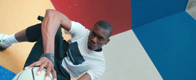 a man holding a basketball in front of a colorful wall