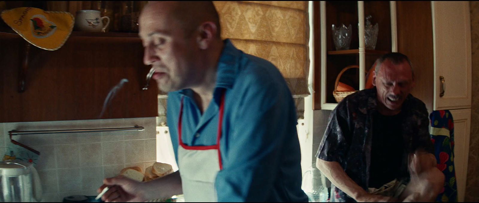 a couple of men standing in a kitchen preparing food