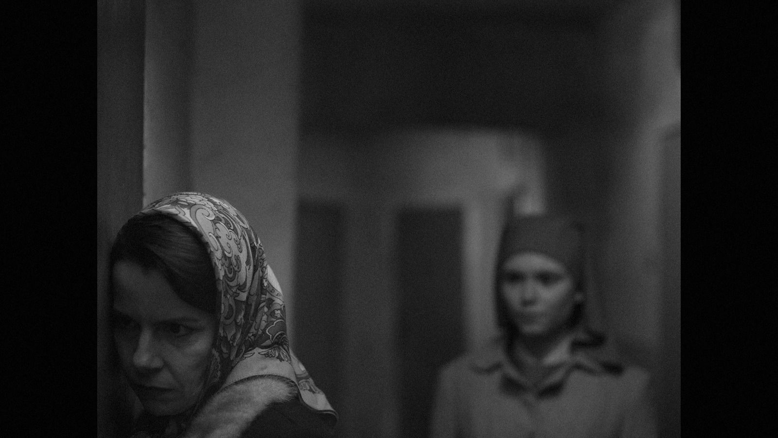 a black and white photo of two women in a hallway