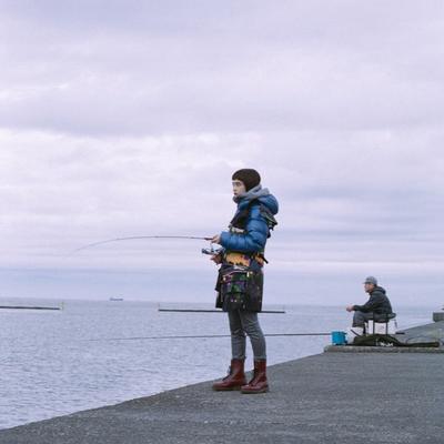 a woman standing on a pier holding a fishing rod