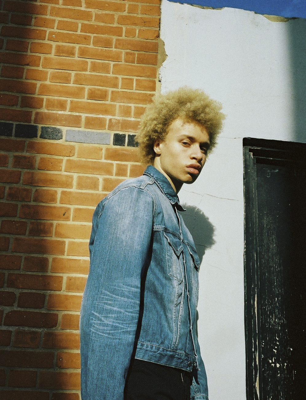 a man standing in front of a brick wall