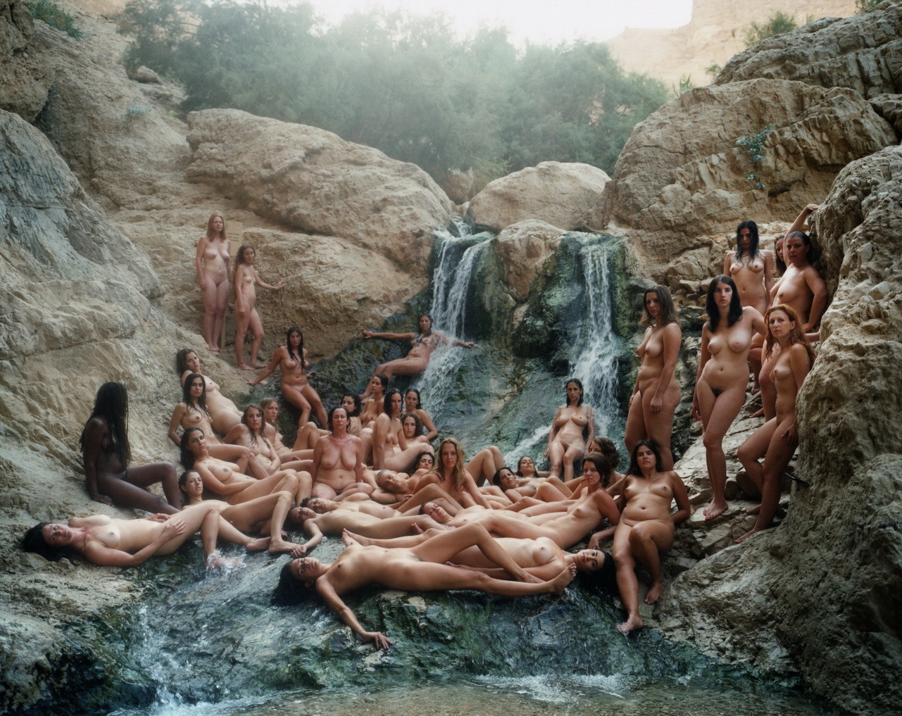 a group of naked women sitting in front of a waterfall