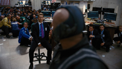 a man in a suit and tie sitting in front of a crowd of people