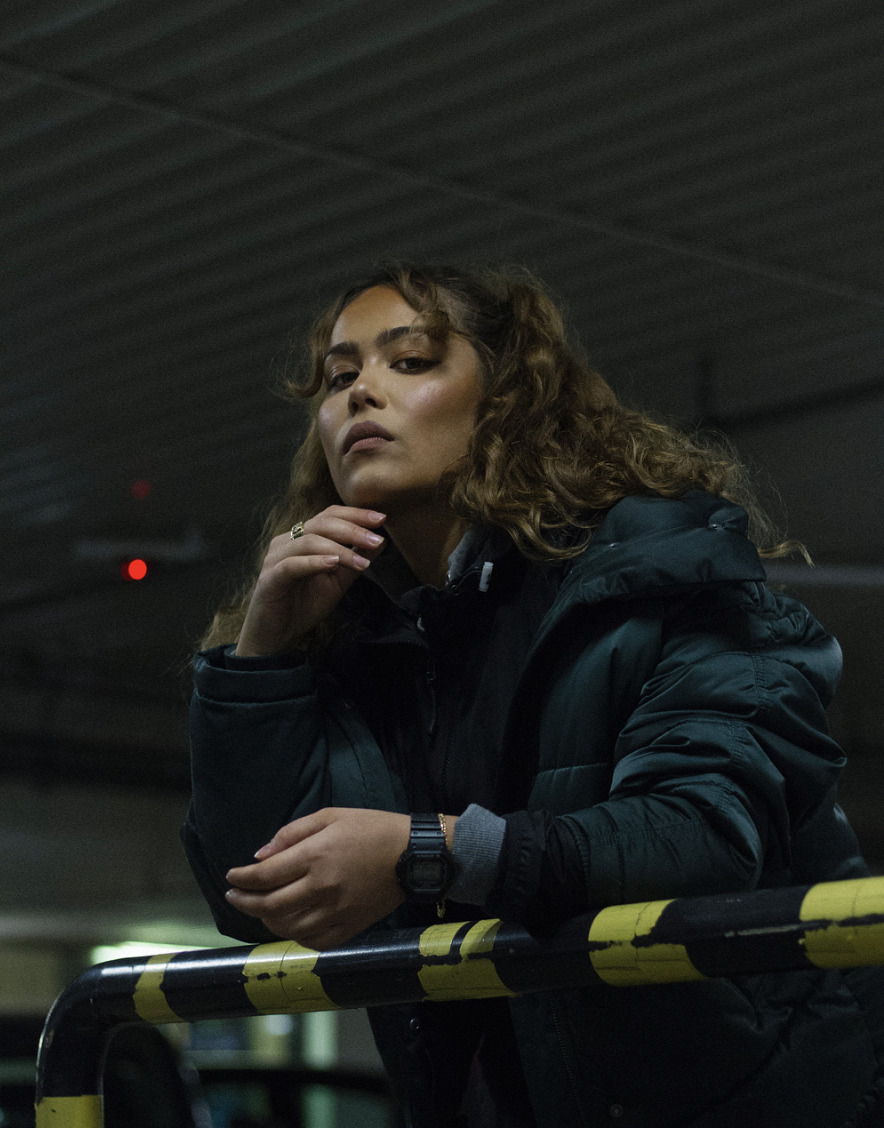 a woman in a black jacket leaning on a rail