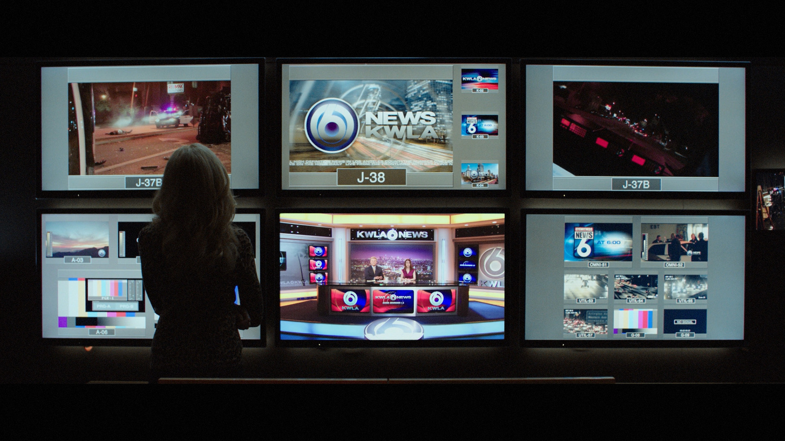 a woman standing in front of multiple television screens