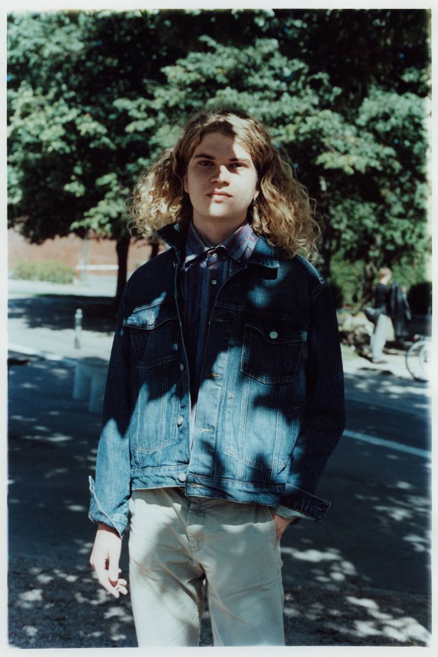 a young man standing in front of a tree