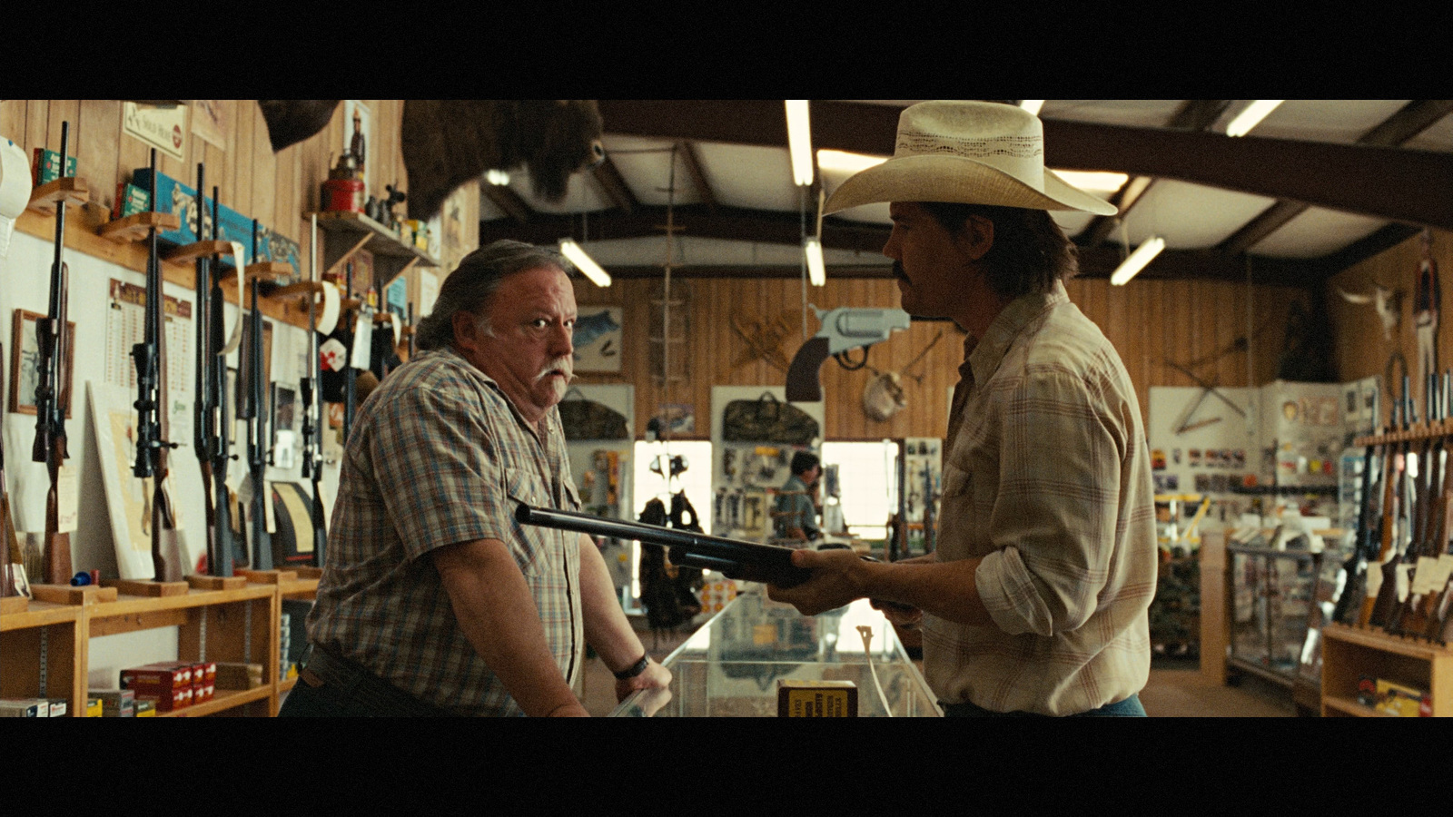 two men standing in a store holding a gun