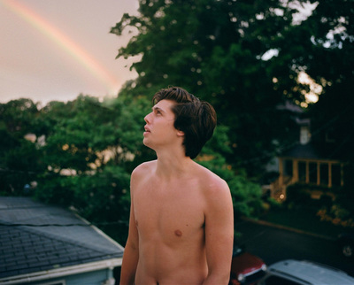 a shirtless young man standing in front of a rainbow