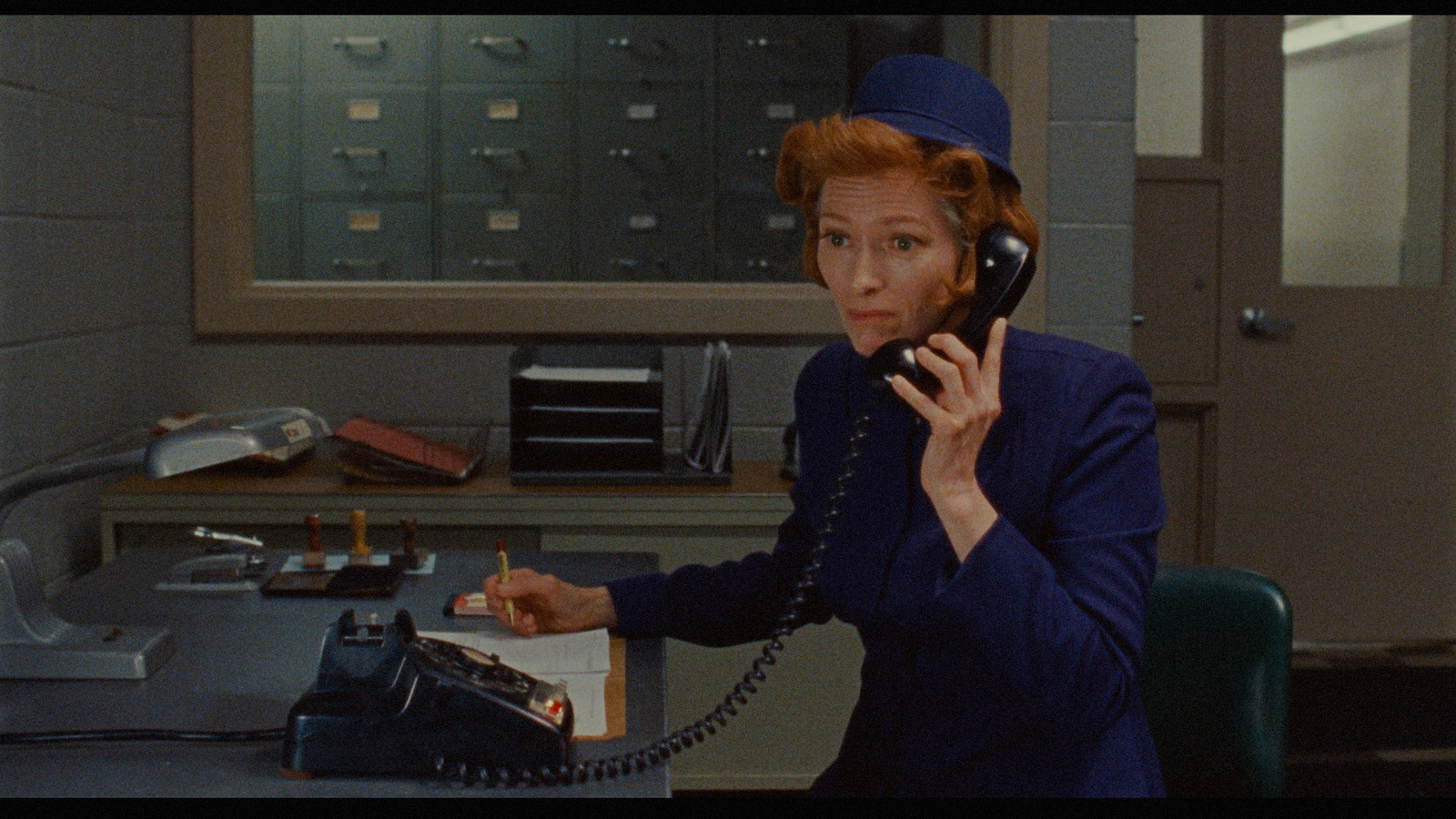 a woman talking on a phone while sitting at a desk