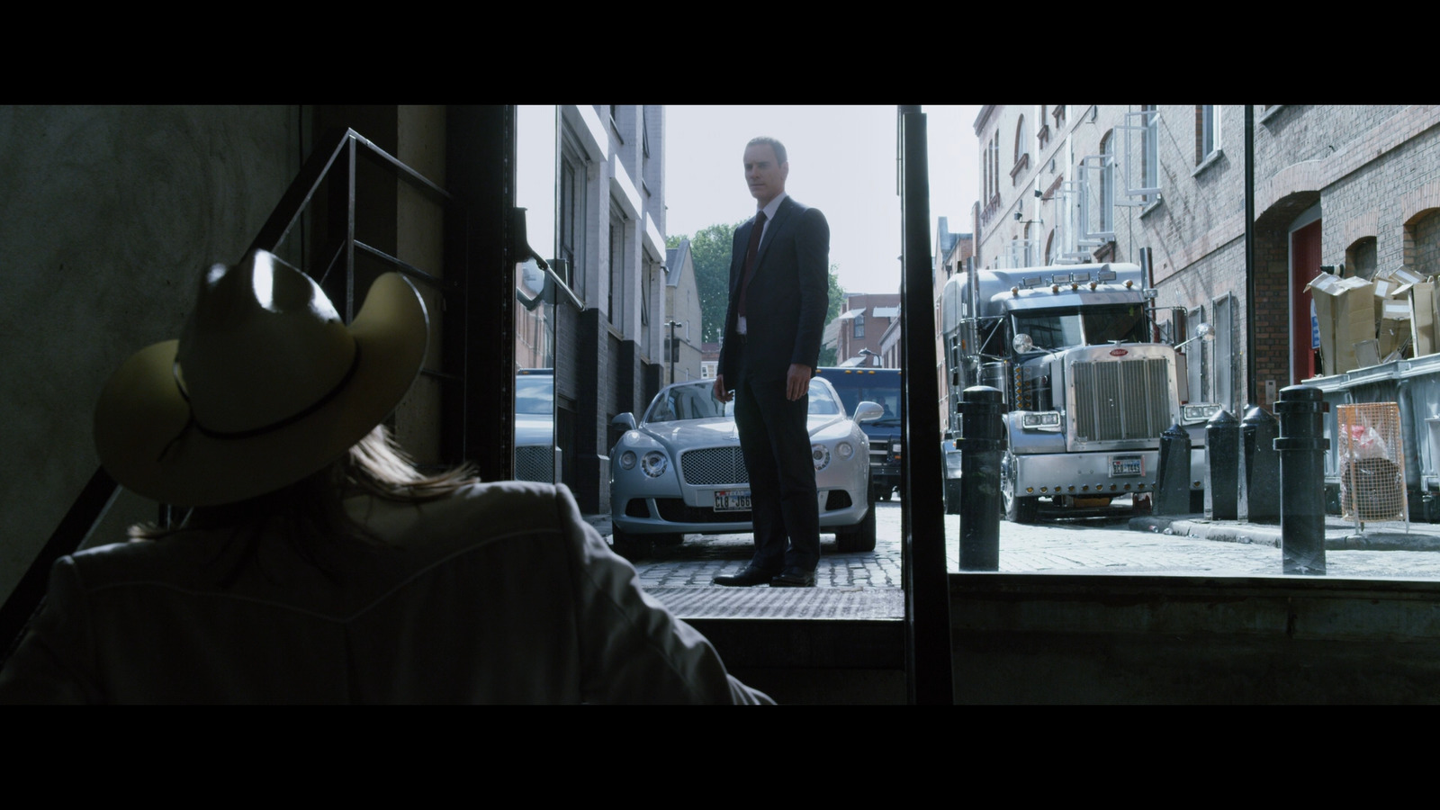 a man standing outside of a building with a truck in the background