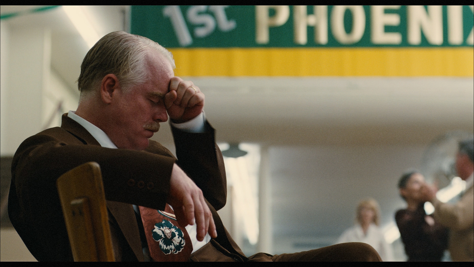 a man sitting in a chair with his hand on his head