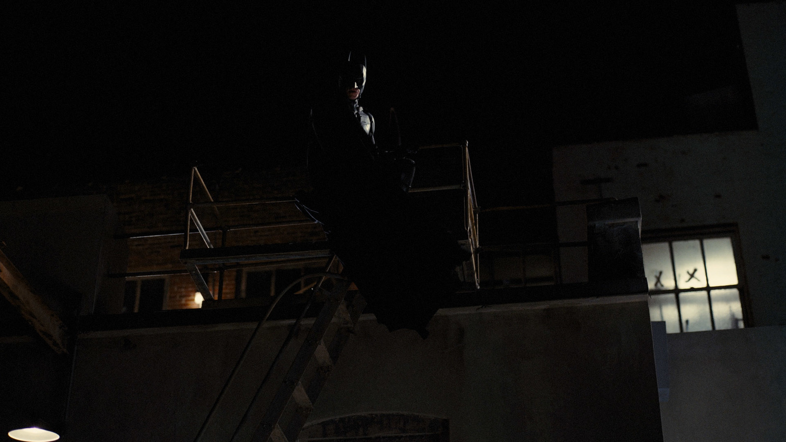 a man standing on top of a ladder at night