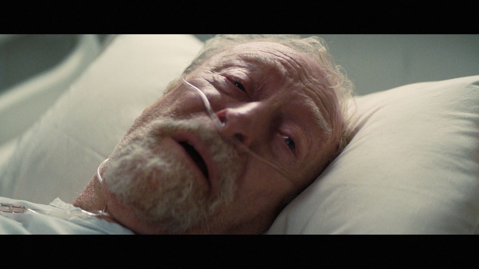 an older man laying in bed with a tube in his mouth