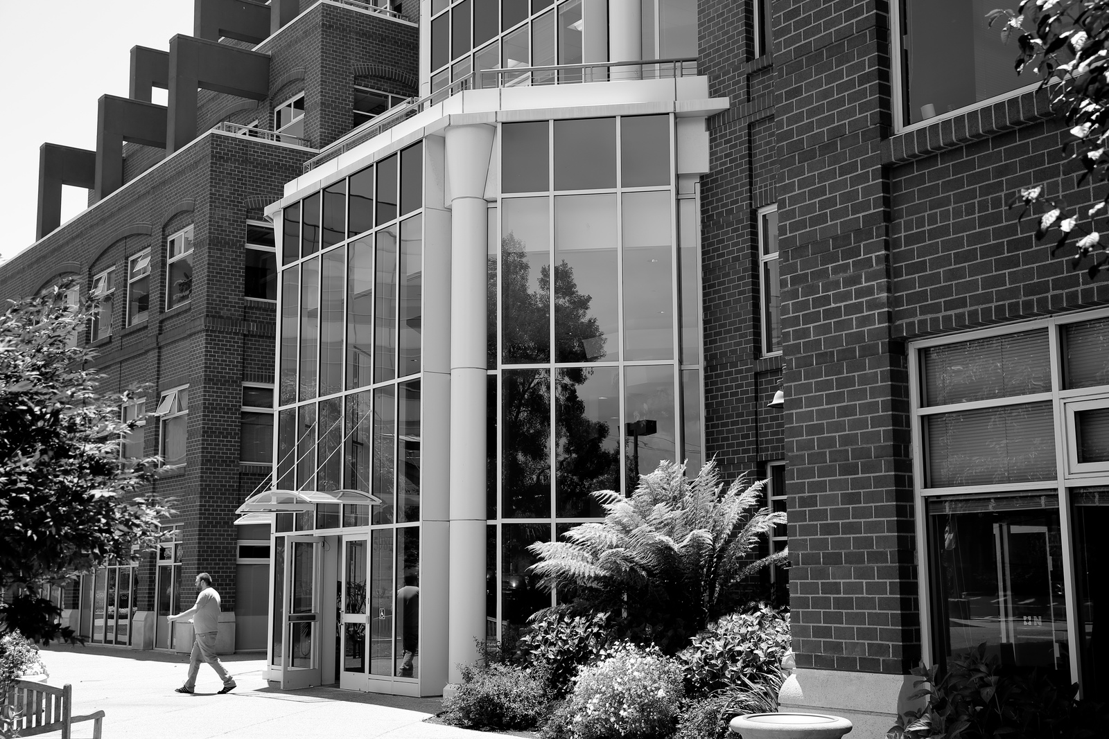 a black and white photo of a person walking by a building