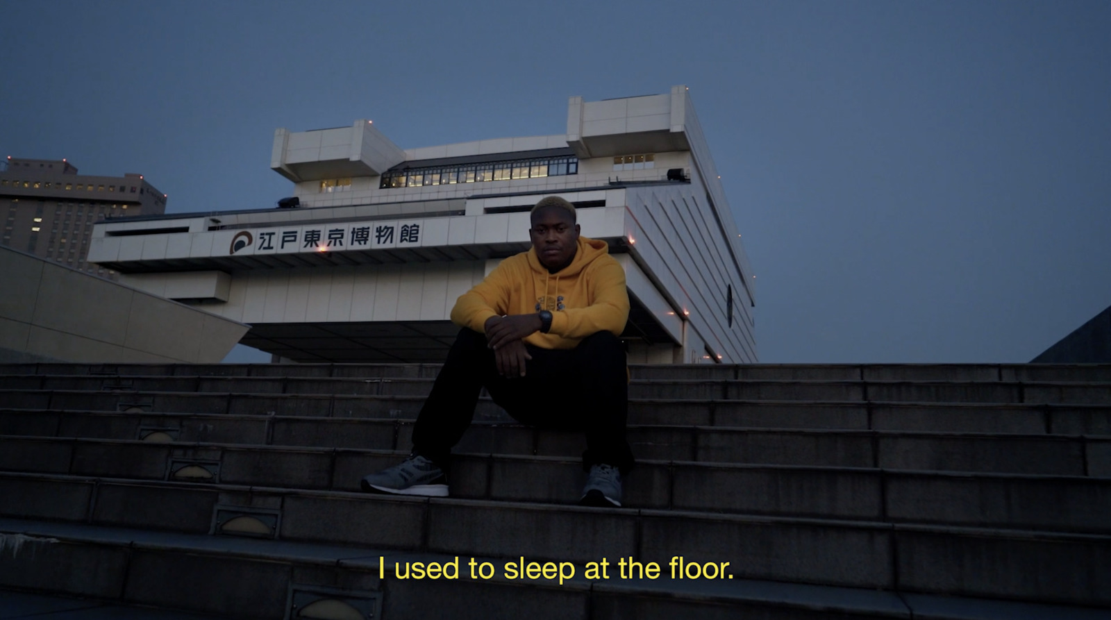 a man in a yellow sweater is sitting on some steps