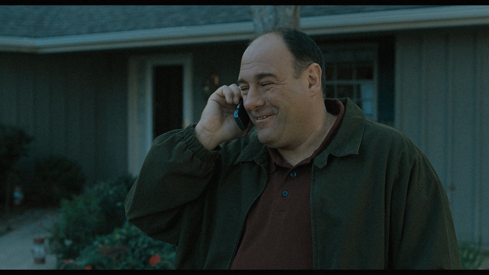 a man talking on a cell phone in front of a house