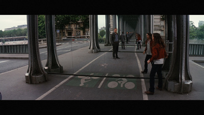 a group of people walking down a street next to tall buildings