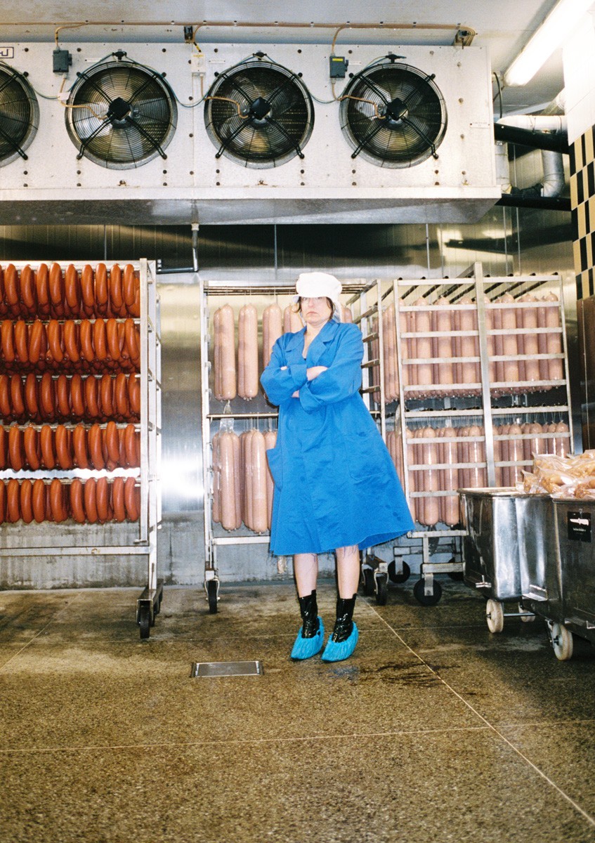 a woman in a blue coat standing in front of a machine