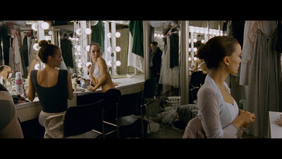 a woman standing in front of a mirror in a dressing room