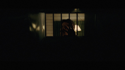 a person standing in front of a window in the dark