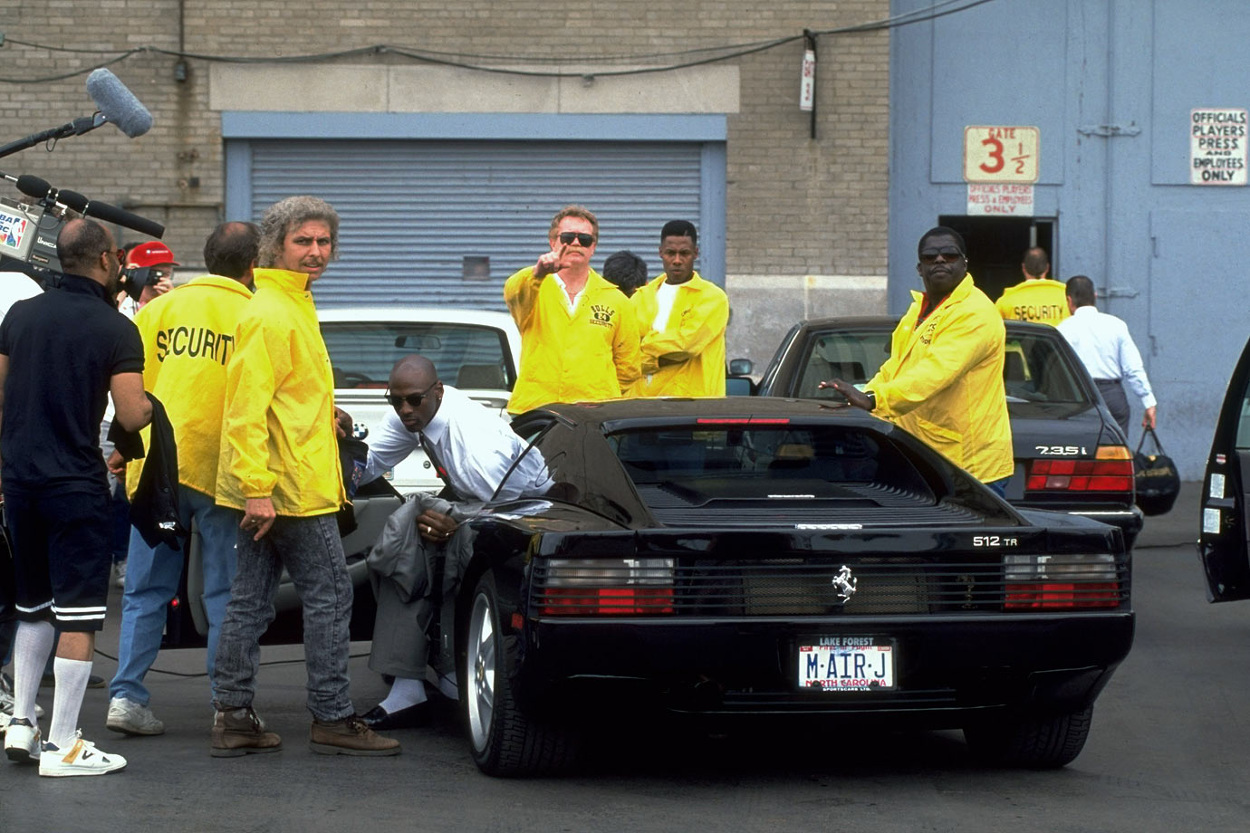 a group of men in yellow jackets standing around a car