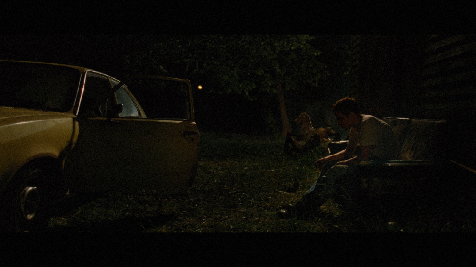 a man sitting on a bench next to a car