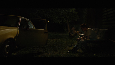 a man sitting on a bench next to a car