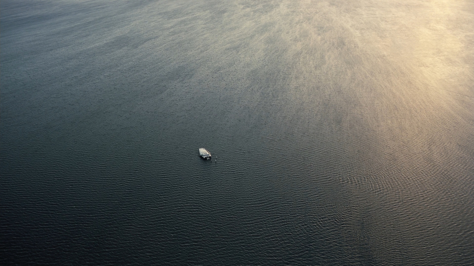 a lone boat floating in the middle of the ocean