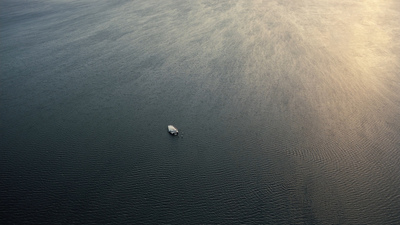 a lone boat floating in the middle of the ocean