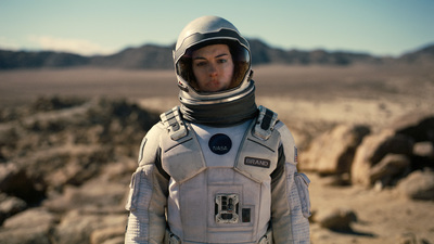 a man in a space suit standing in the desert